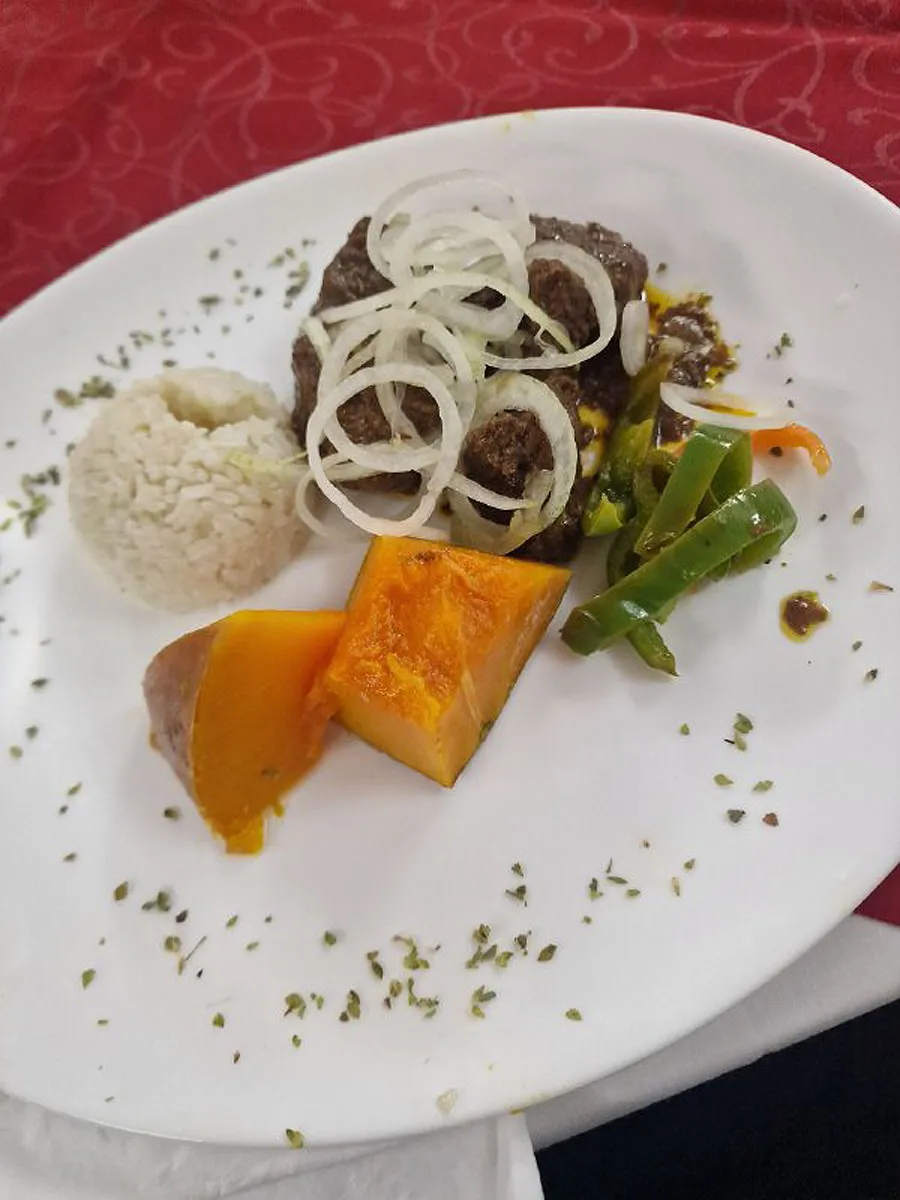 Вареный рис в форме шарика, жареное мясо кусковое посыпанное кольцами лука.