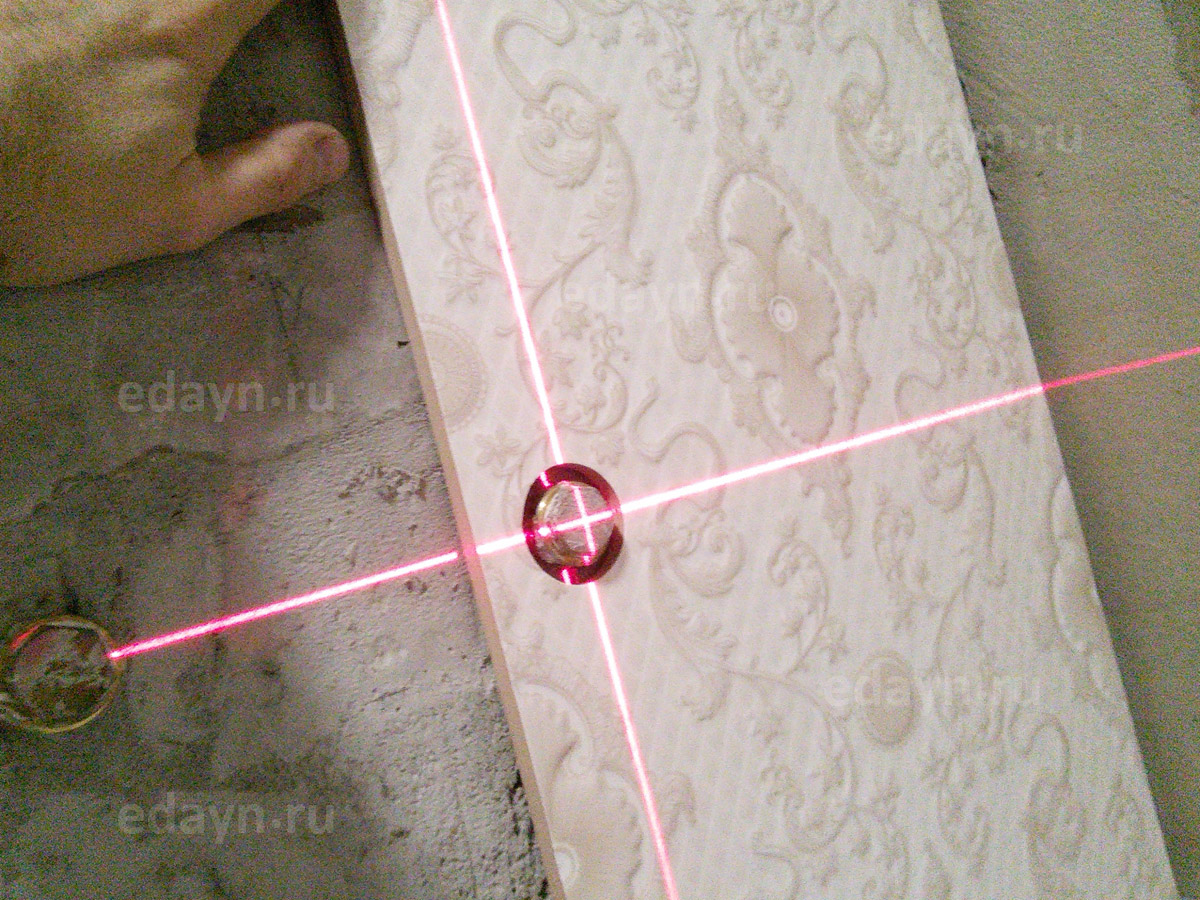 Перекрестье лазерного уровня точно в центре отверстия плитки.